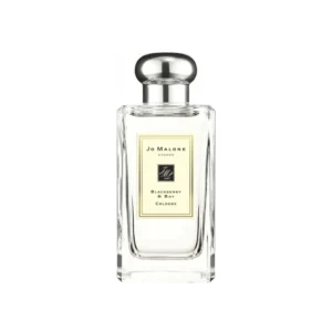 Przejrzysty flakon Jo Malone Blackberry & Bay 100ml w otoczeniu ciemnych owoców i zielonych liści.